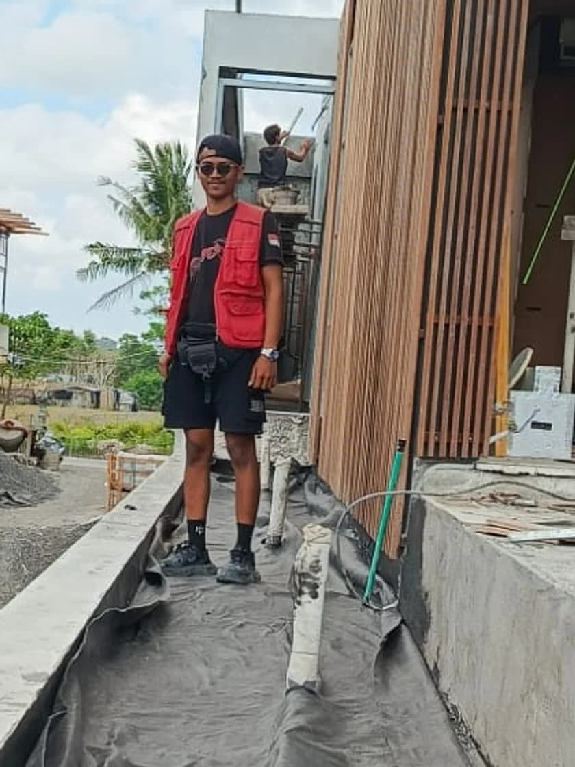 Kadek on a construction site in Bali, wearing a red work vest