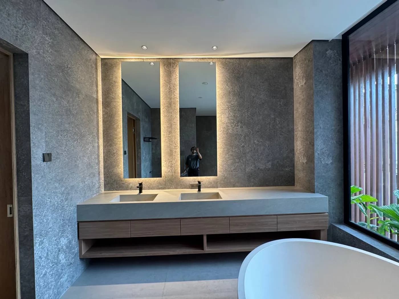 Double vanity with backlit mirrors and stone-textured walls